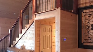 Un interior de madera con una escalera, un sofá de cuero y una puerta que da a otra habitación.