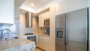 Een moderne keuken met roestvrijstalen apparatuur, een marmeren aanrechtblad en een inbouwoven.