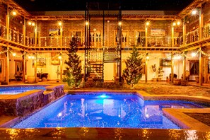 Un patio con piscina, balcones de madera y adornos navideños.