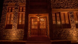 A stone building with a wooden door and windows, illuminated at night.