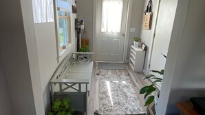 A hallway with a wooden floor, a white door, a small bench, and a potted plant. - Cozy cottage loft on the quiet side of Mount Desert Island -Now booking for 2026 (Tremont)