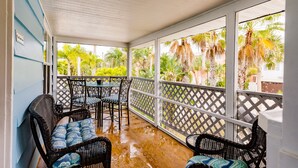A covered outdoor area with wicker furniture and a view of palm trees. - Heated Pool, 4 Houses to Beach (Siesta Key)