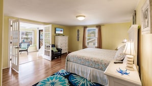 A bedroom with a bed, a nightstand, a chair, a dresser, and a television. - Heated Pool, 4 Houses to Beach (Siesta Key)