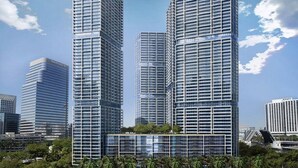 Un immeuble moderne de grande hauteur, doté d’une façade en verre, entouré de palmiers et d’autres bâtiments.