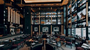 Un restaurant doté d’un espace central où sont disposées les tables, entouré d’étagères ornées d’objets décoratifs.