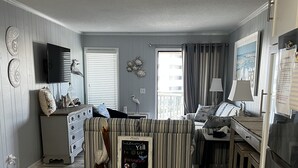 A compact living space with a kitchenette, a striped sofa, a small table, and a chalkboard sign.