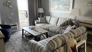 A living room with striped sofas, a coffee table, and a painting of a beach scene.