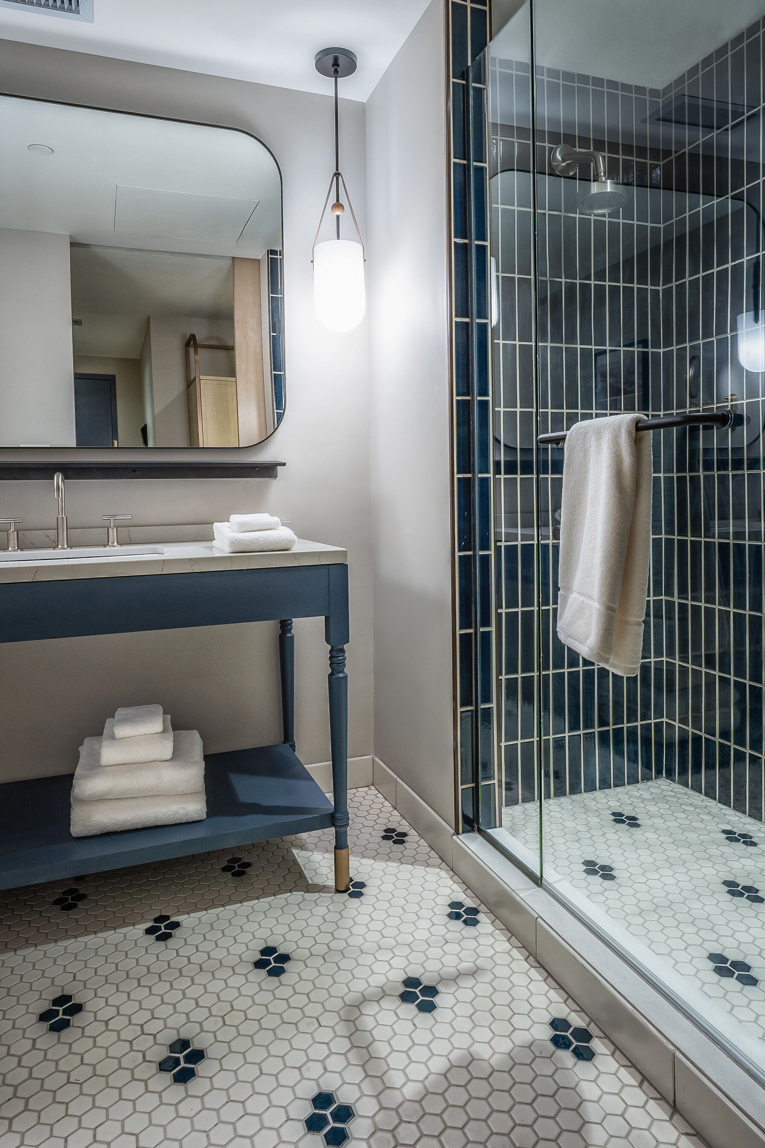 Ein Badezimmer mit Glasdusche, Waschbecken mit Spiegel und Handtuchhalter.