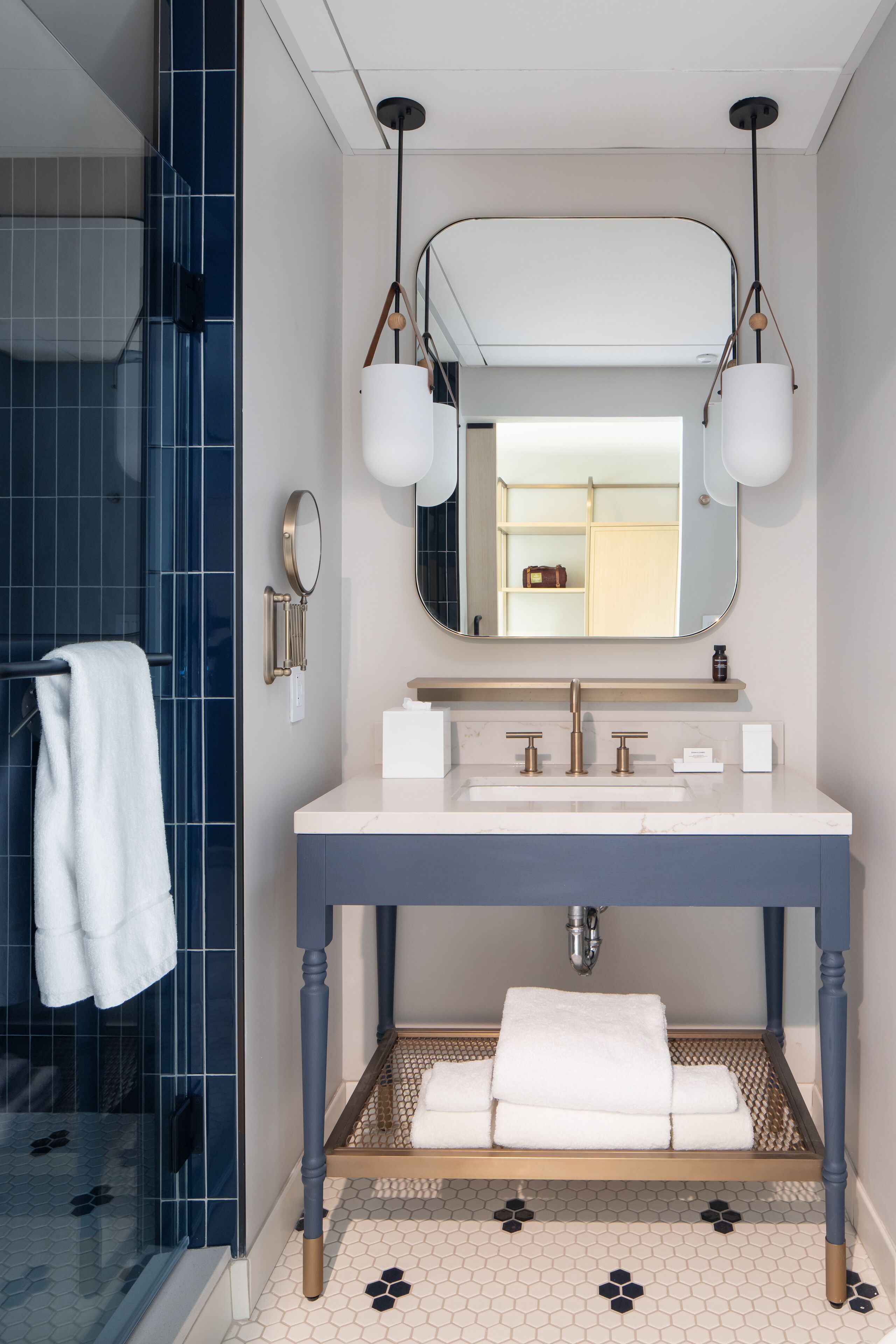 A modern bathroom with a large mirror, two sinks, and a shower area.