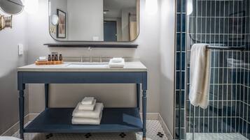 Un baño moderno con tocador azul oscuro, un espejo grande y ducha con mampara de vidrio.