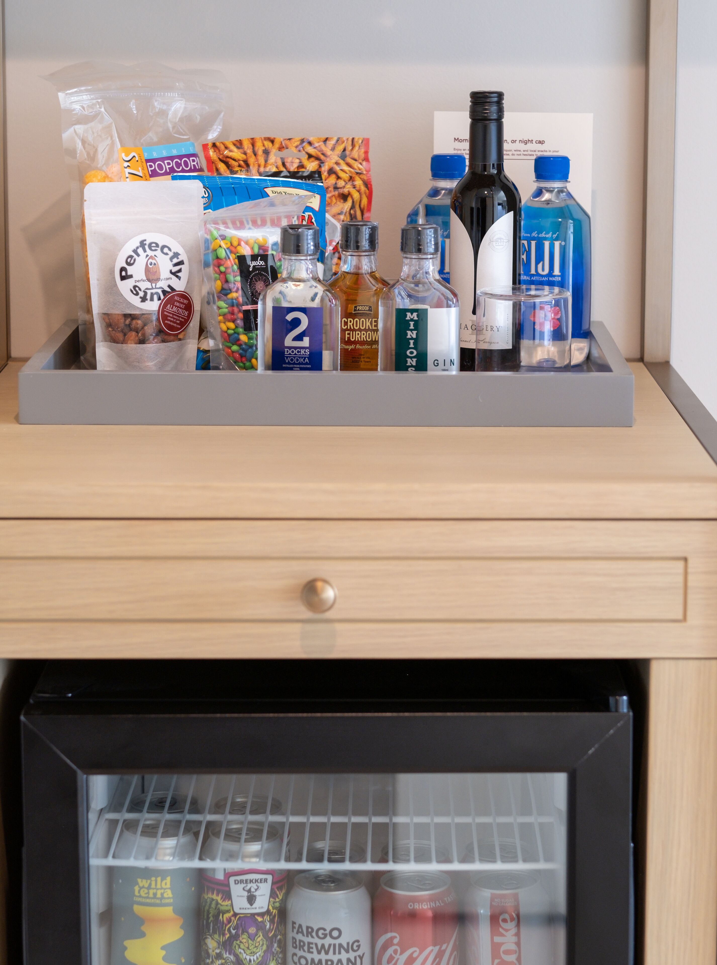 A minibar with snacks, drinks, and a bottle of alcohol.
