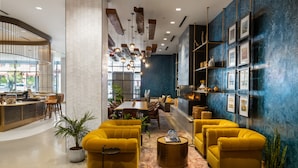 Eine moderne Lobby mit gelben Sofas, einem Essbereich und einer Bar.
