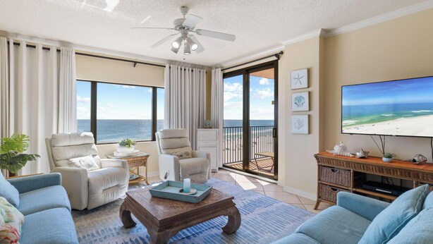 A spacious living room with a large TV, comfortable seating, and a view of the ocean. - Four Seasons 703E by Liquid Life (Orange Beach)