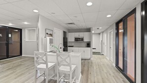A modern kitchen with white cabinetry, a central island with seating, and a microwave above the sink. - Four Seasons 703E by Liquid Life (Orange Beach)