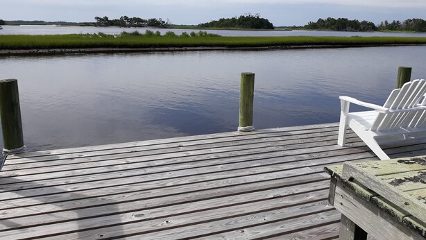 Un muelle de madera con una silla blanca.