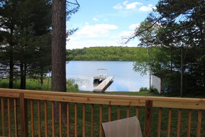 Eine Holzterrasse mit Blick auf einen ruhigen See, eine Steg ragt ins Wasser hinein.