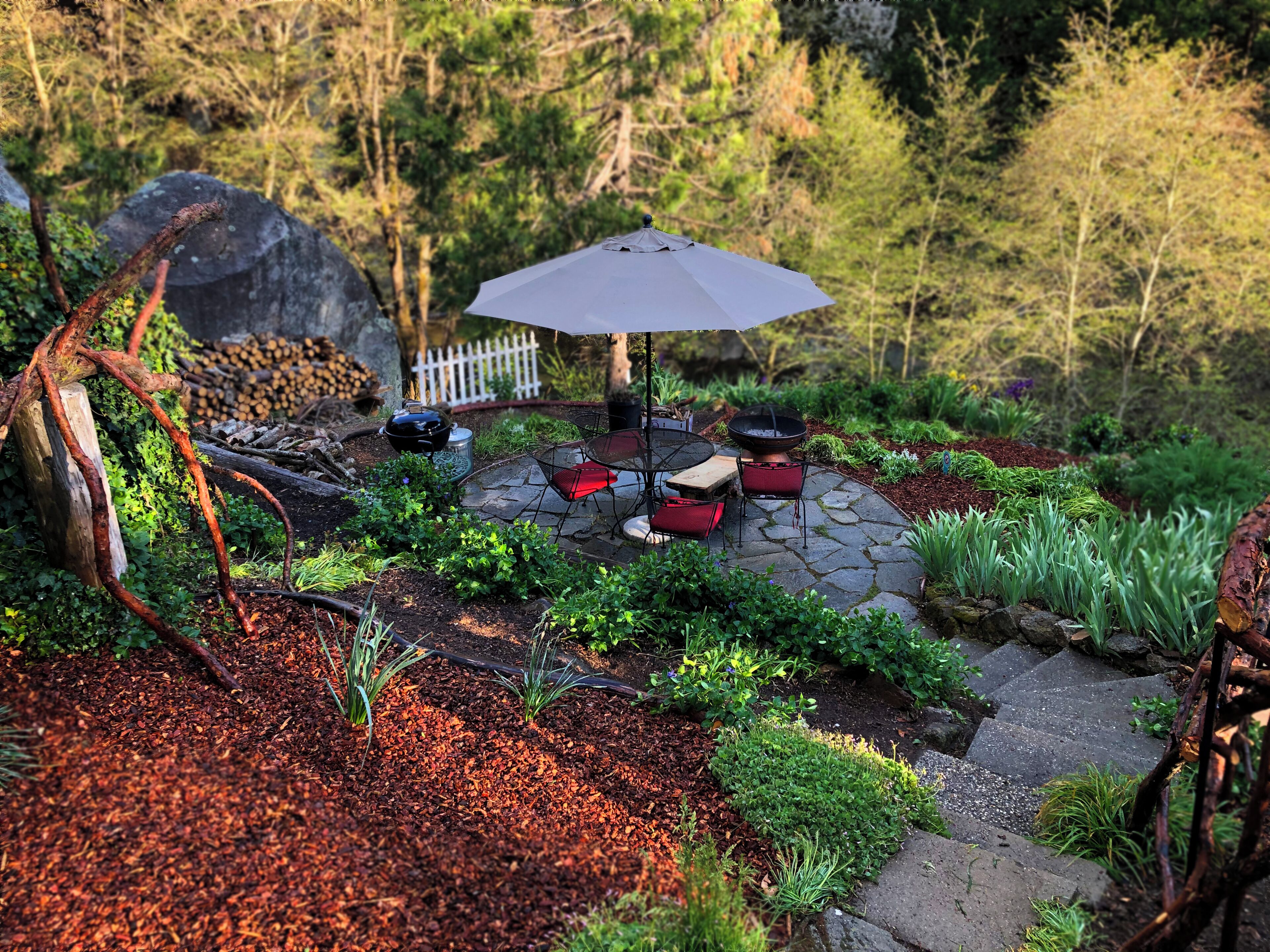 A patio with stone flooring, a table with chairs, and a large umbrella.