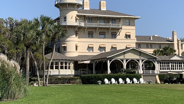 A large, multi-story building with a prominent tower, multiple balconies, and a well-maintained lawn. - Sea-Esta Retreat, a Great Golden Isles Location! (St. Simons Island)