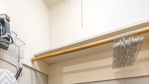 Ein kleines Zimmer mit Staubsauger, Bügelbrett und einer Stehleiter.