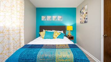 Un dormitorio con cama, mesita de noche, lámpara y decoración en la pared.
