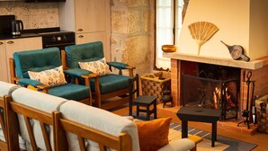 Una sala de estar acogedora con chimenea, dos sillones color turquesa, un sofá de madera y una mesita.