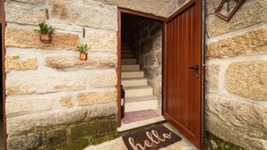 Una pared de piedra con una puerta de madera y una escalera que lleva a un nivel superior.
