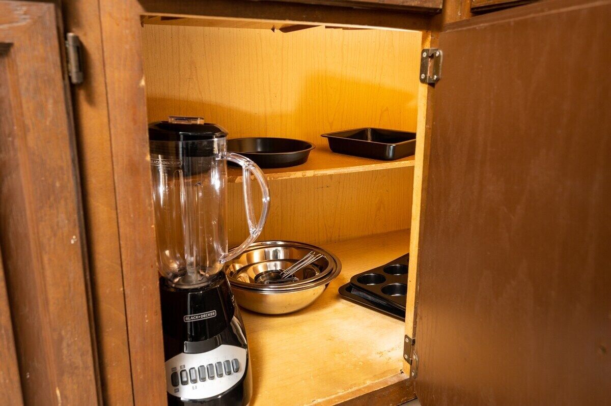 A kitchen with a blender, a metal bowl, a black pan, and a muffin tray.