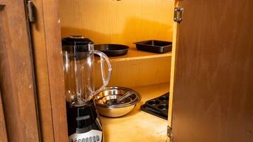 A kitchen with a blender, a metal bowl, a black pan, and a muffin tray.