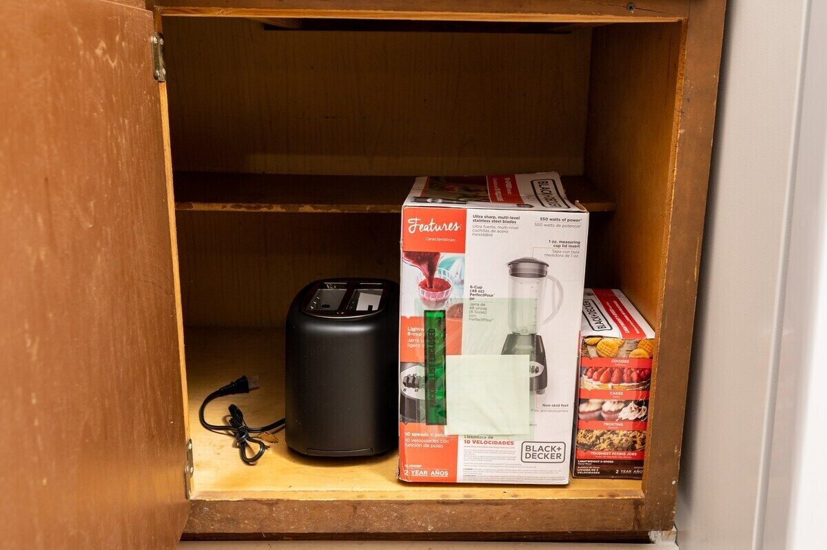 Un armario de cocina con un tostador, una licuadora y una caja de cereales.