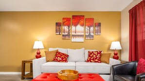 A living room with a sofa, two side tables with lamps, a red ottoman, and a red leather chair. - Near Hospitals | P&G | 3 TVs | King 🛏 | PetsOK🐩 (Pineville)