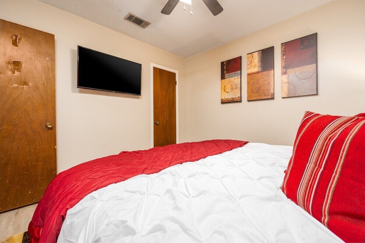 A bedroom with a bed, a television, and two doors.