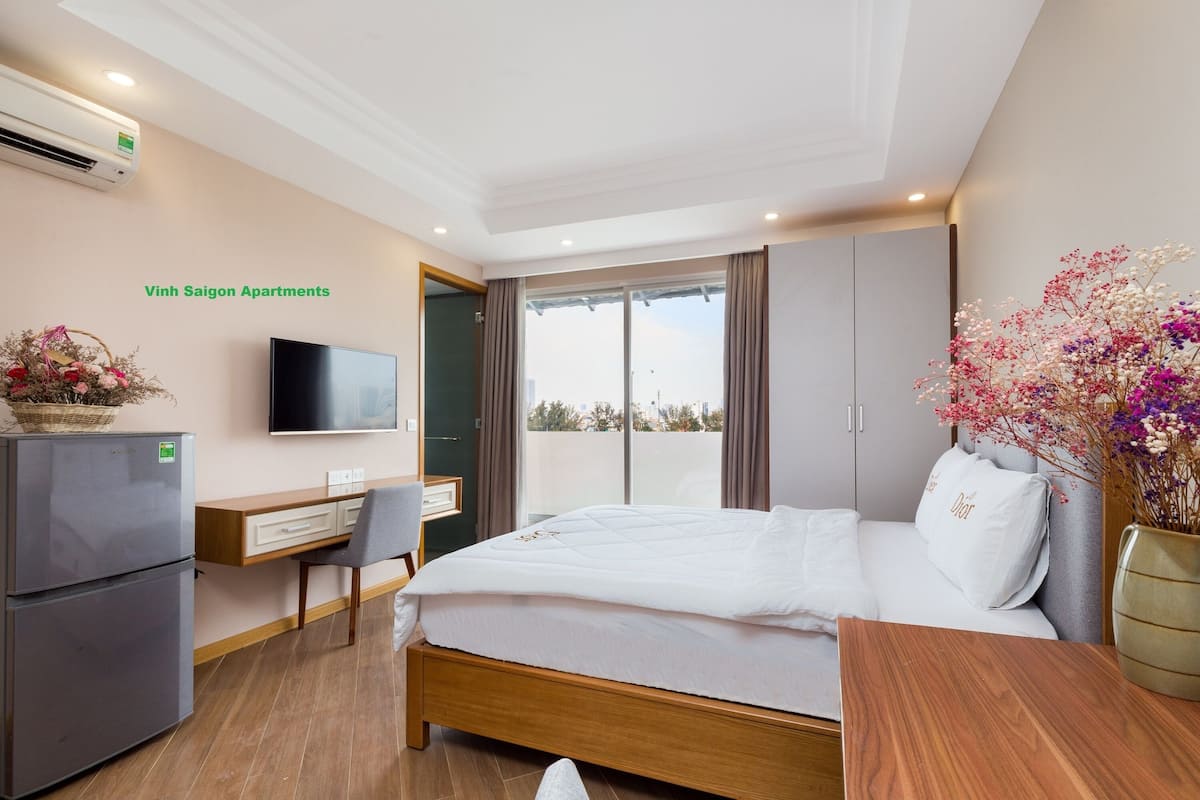 A bedroom with a bed, a desk, a chair, a TV, and a refrigerator.