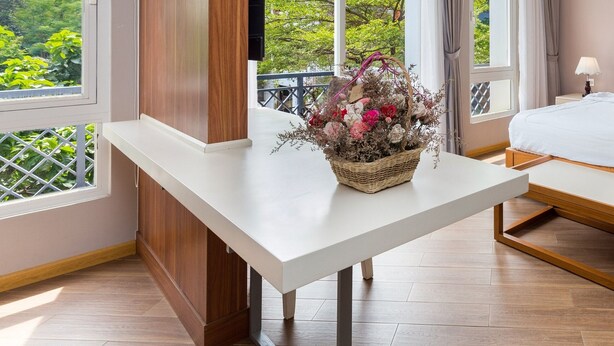 A bedroom with a bed, bedside table, and a view of greenery outside. - Vinh Saigon SECC 2 (Ho Chi Minh City)