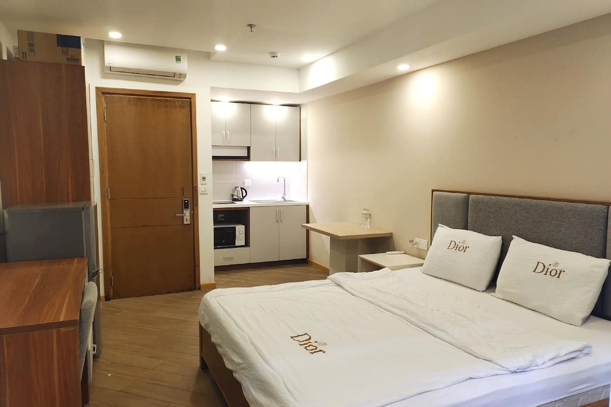 A hotel room with a bed, a desk, a kitchenette, and a wardrobe.