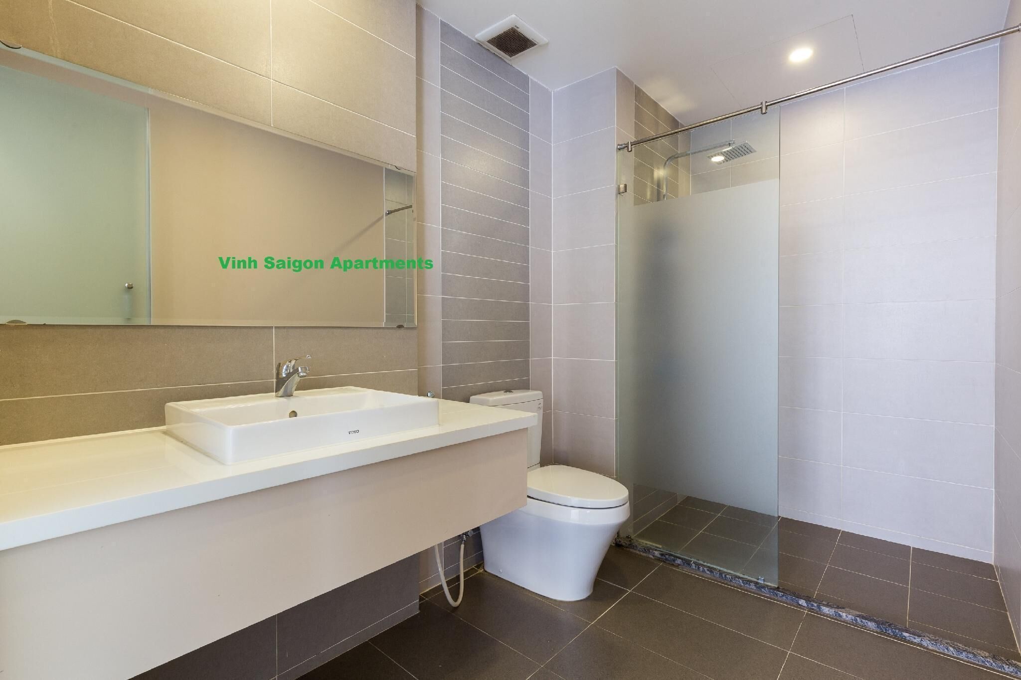 A modern bathroom with a sink, toilet, and glass shower enclosure.