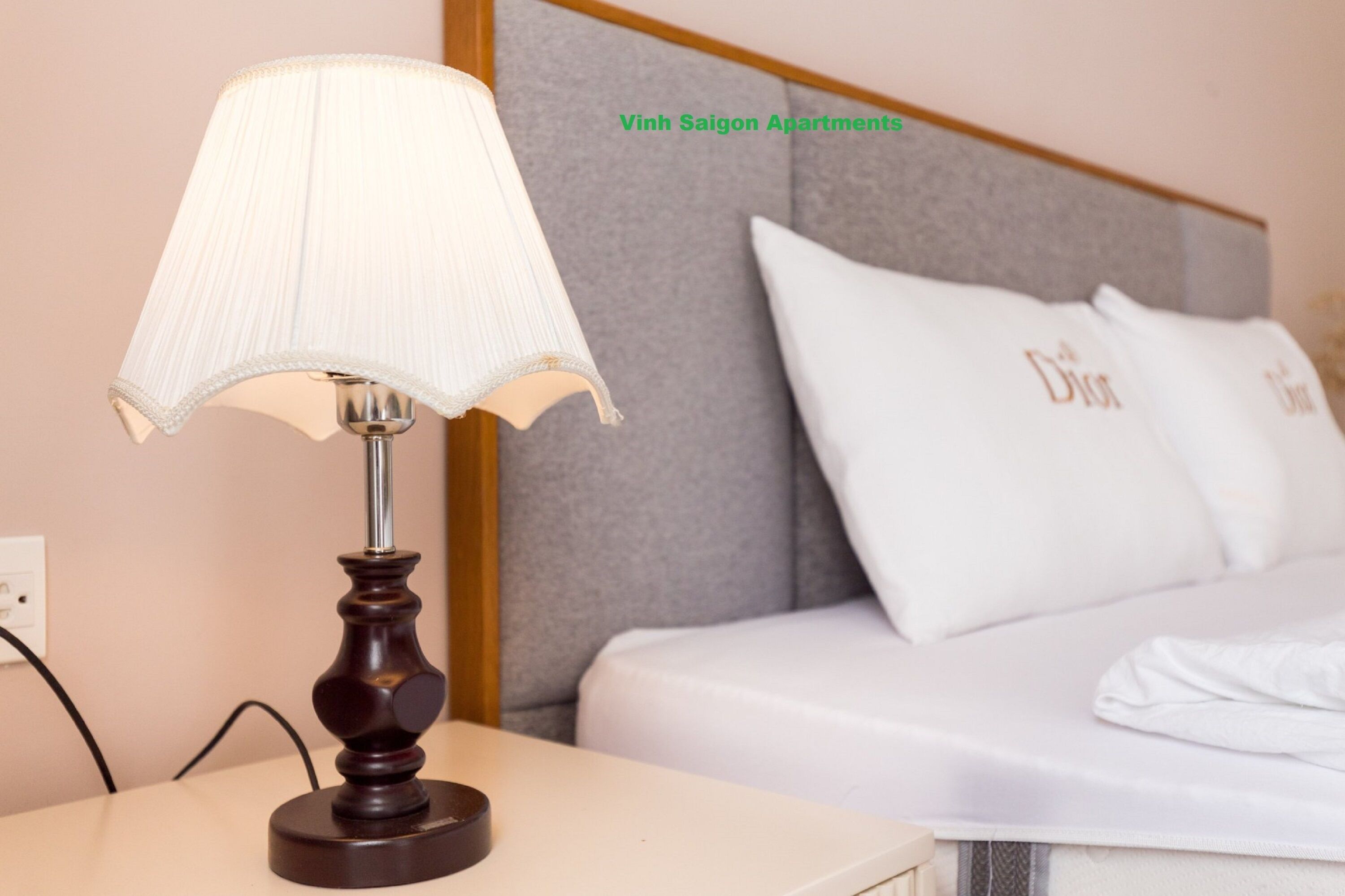 A hotel room with a bed, a nightstand with a lamp, and a wall with a headboard.