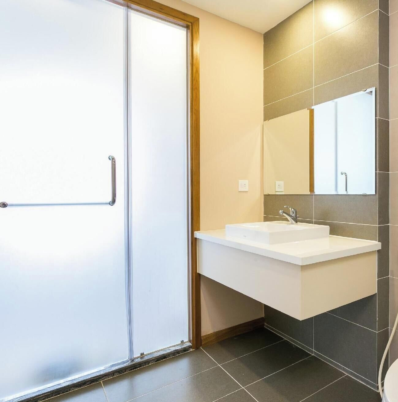 Une salle de bain moderne avec un lavabo, un miroir et des toilettes, le tout de couleur blanche.