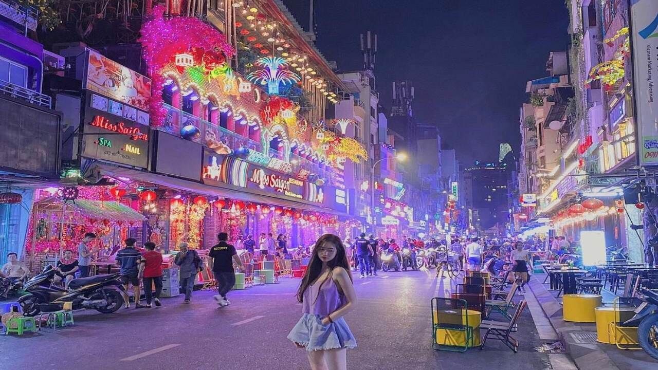 A brightly lit street with neon signs and storefronts.