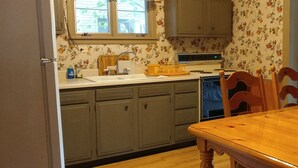 Une cuisine avec des meubles de rangement en bois, un évier, une cuisinière et une table à manger avec des chaises.