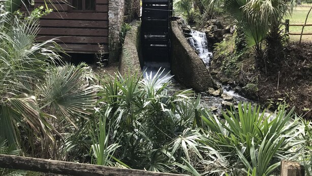 Un edificio rústico de madera con pared de piedra y una pequeña cascada.