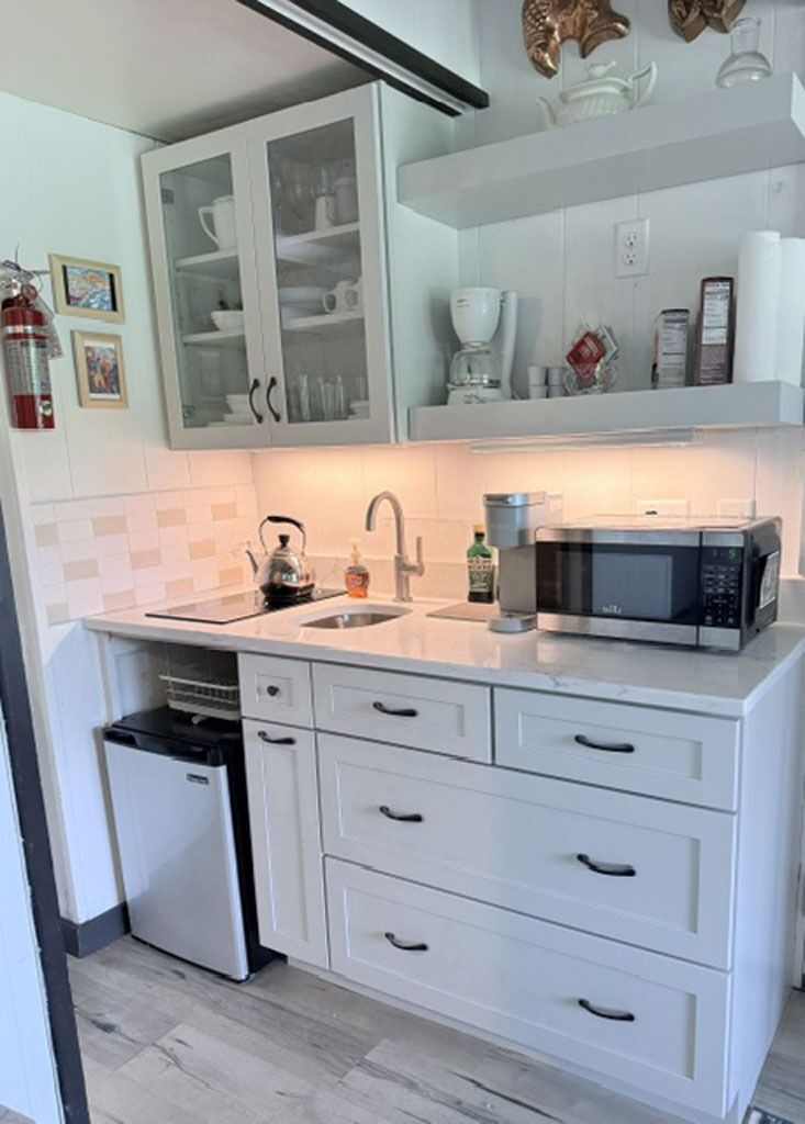 Een moderne keuken met witte kastjes, een inbouwmagnetron en een kleine vaatwasser.