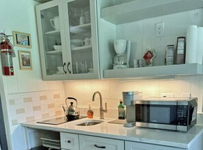 A kitchen with a double sink, a kettle, a coffee maker, and a microwave.