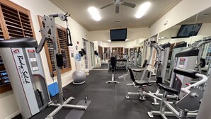A gym with various exercise equipment, a large mirror, and a ceiling fan. - Regatta at Vanderbilt is an upscale condo - a 7 minute walk to the beach! (Naples)