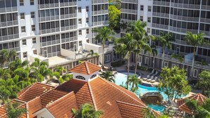 A hotel with multiple balconies, a swimming pool, and palm trees. - Regatta at Vanderbilt is an upscale condo - a 7 minute walk to the beach! (Naples)