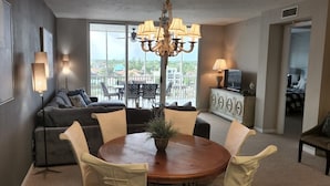 A modern living room with a round dining table, a sofa, and a balcony with a view. - Regatta at Vanderbilt is an upscale condo - a 7 minute walk to the beach! (Naples)