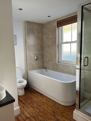 Ein modernes Badezimmer mit einer freistehenden Badewanne, einer Toilette und einer Duschkabine aus Glas.