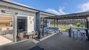 A modern outdoor patio with seating, a pergola, and a view of a park. - Three Bedroom Townhouse (Motueka)