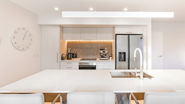A modern kitchen with a large island, stainless steel appliances, and a clock on the wall. - Three Bedroom Townhouse (Motueka)