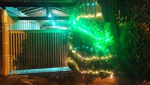 Ein Gebäude mit einem verschlossenen Eingang, einem überdachten Bereich mit Dach und einem Weihnachtsbaum, der mit Lichtern und Schmuck verziert ist.