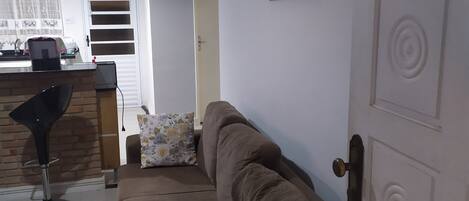 A living room with a brown sofa, a patterned pillow, a modern pendant light, and a door with decorative molding.